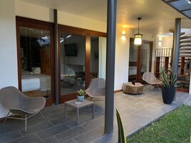 Eine Terrasse mit Sitzgelegenheit, einem kleinen Tisch und einem Blumentopf.