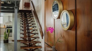 Eine Holztreppe mit modernem Design, eine Holzwand mit zwei runden Spiegeln und eine Vase mit Blumen.