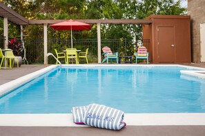 A swimming pool with a towel labeled "Bilexi, MS" on the edge, surrounded by colorful chairs and a red umbrella. - Home2 Suites by Hilton Biloxi North/D'Iberville (D'Iberville)