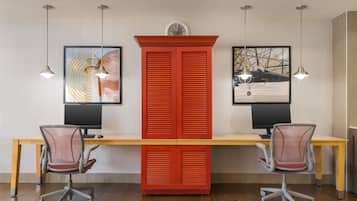 A modern office space with a long desk, two office chairs, and two pendant lights.