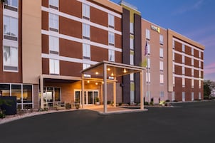 Un hotel moderno con entrada cubierta, varios pisos y una bandera estadounidense.