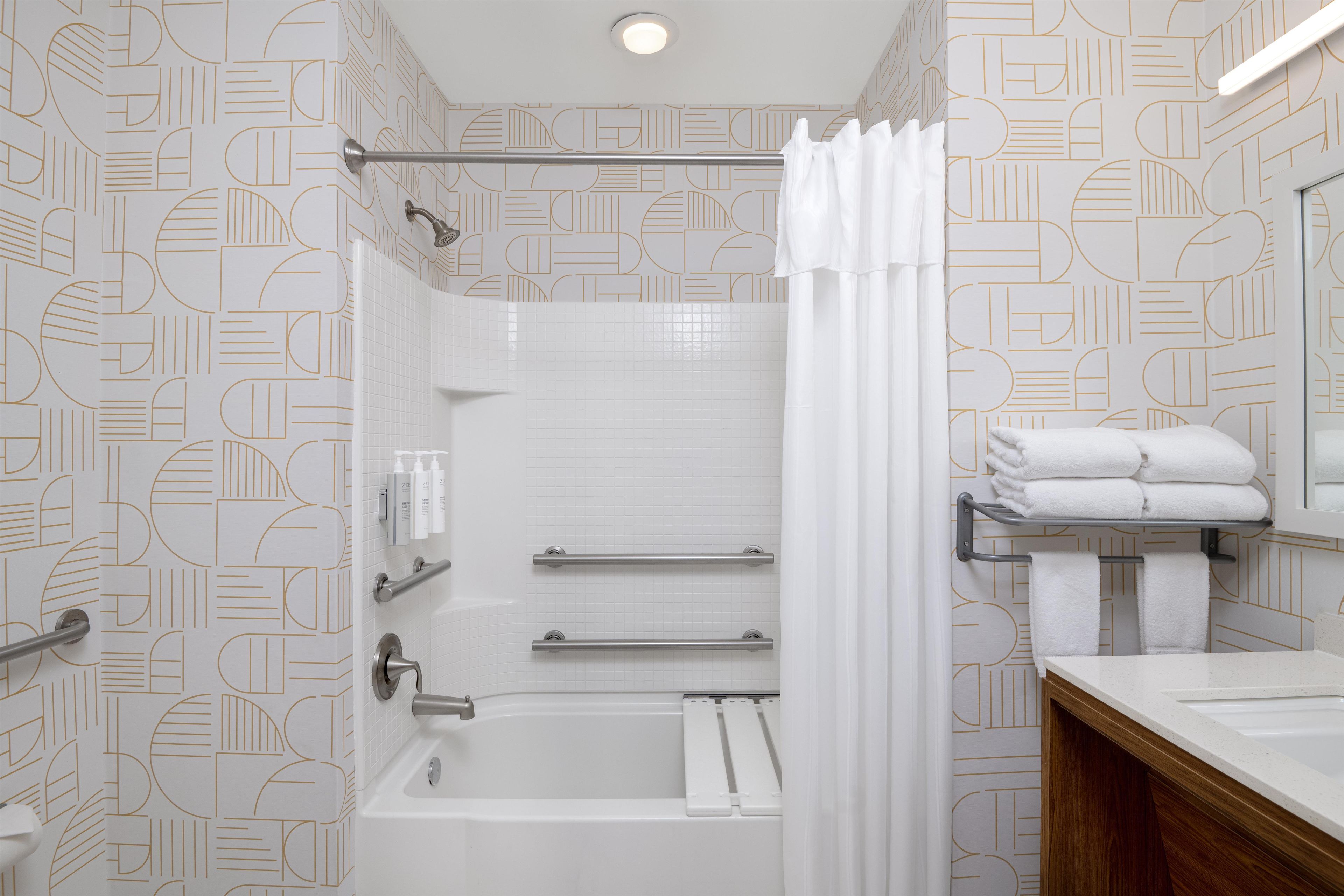 Une salle de bain moderne équipée d’une baignoire, d’une douche et d’un meuble-lavabo avec un miroir.