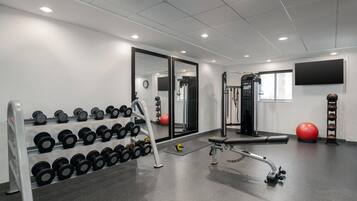 A gym with weightlifting equipment, a bench, and exercise balls.
