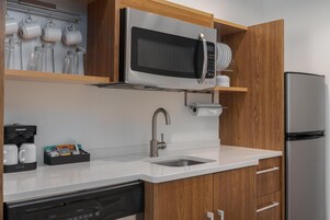 A modern kitchen with a built-in microwave, stainless steel sink, and wooden cabinets.