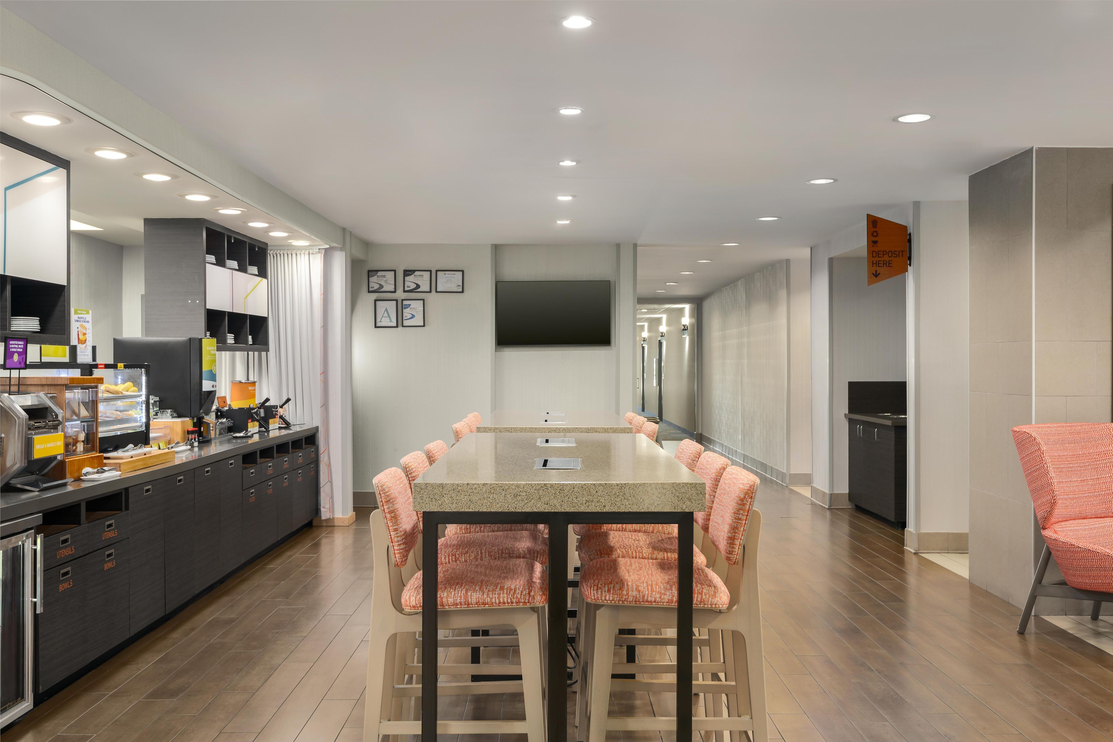 A modern kitchen with a long counter, built-in appliances, and a dining area with a table and chairs.