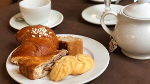 A breakfast setting with a croissant, a pastry, and a teapot on a table. - Hotel da Raffaele (Ischia)