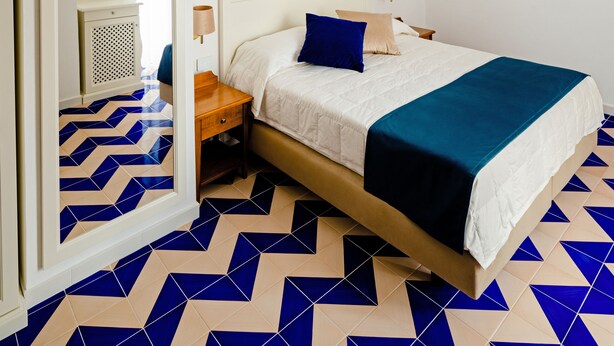A bedroom with a bed, a mirror, a nightstand, and a dresser. - Hotel da Raffaele (Ischia)