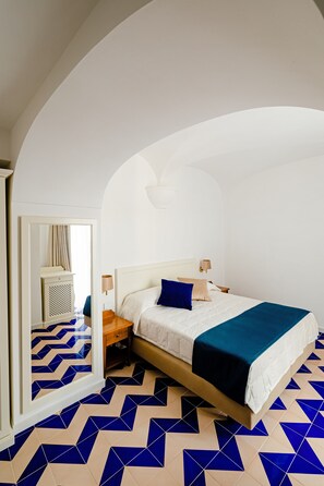 Un dormitorio con una cama, un espejo, una mesita de noche y un aparador.