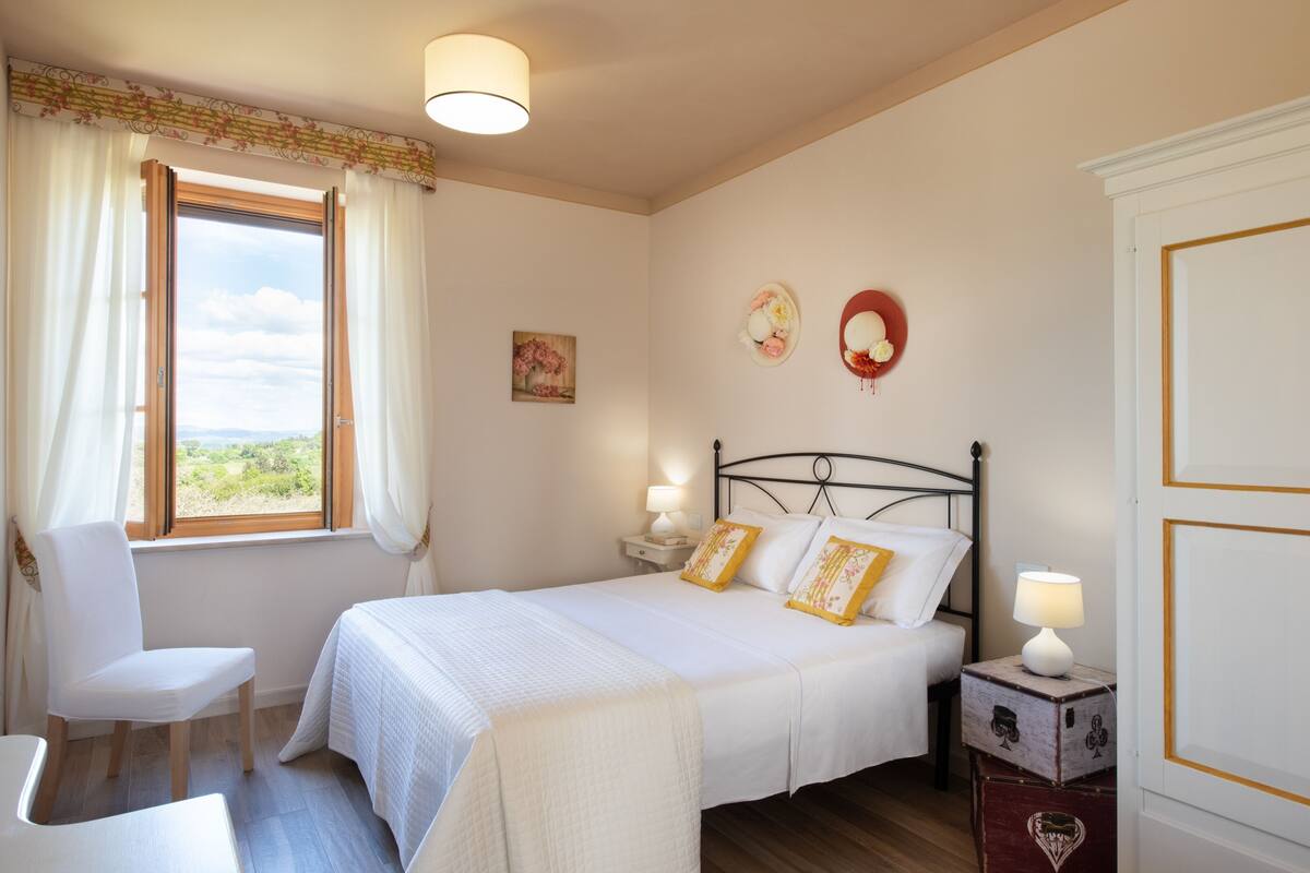 A bedroom with a bed, bedside tables, a chair, and a window with curtains.
