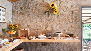 Una pared de piedra rústica con un mostrador de madera que exhibe diversos alimentos y una máquina de café.