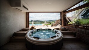 A hot tub in a room with a view of a pool and garden.