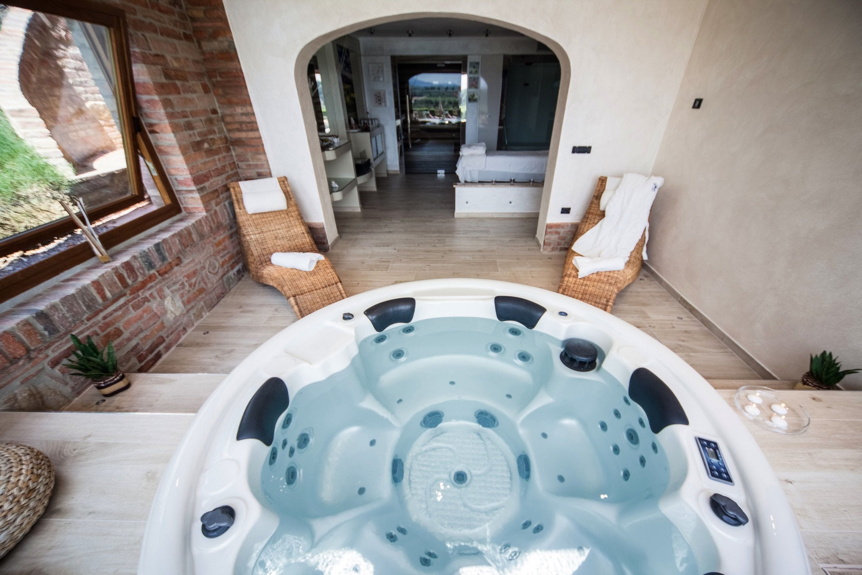 Un espace détente avec un jacuzzi, des fauteuils en osier et une vue sur la pièce en arrière-plan.