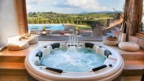 A hot tub with a view of a pool and landscape.