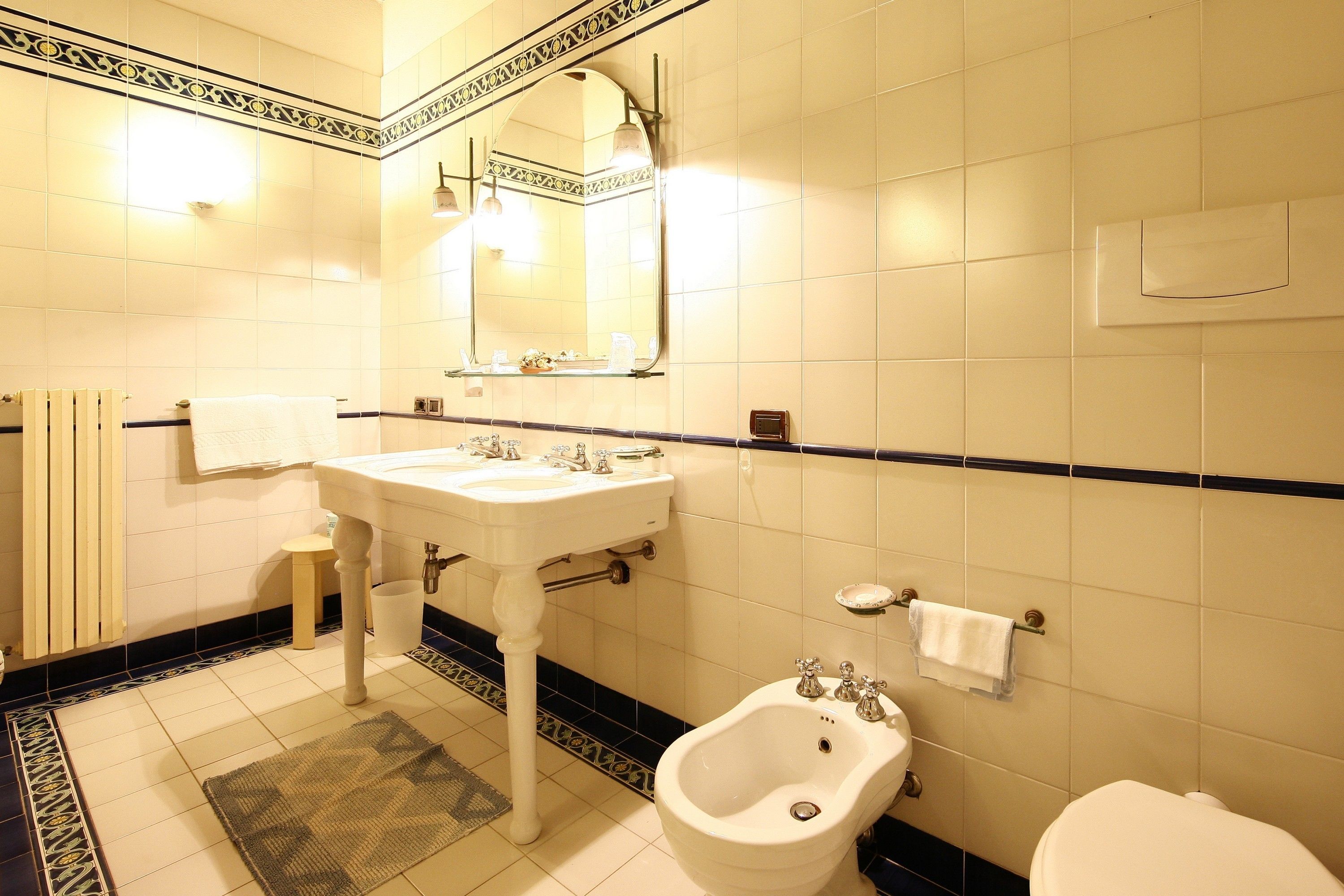 A bathroom with a white sink, a bidet, a toilet, and a mirror.