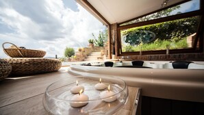 A modern interior with a glass table holding candles, a woven basket, and a stone bench.