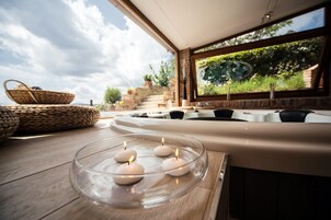 A modern interior with a glass table holding candles, a woven basket, and a stone bench.