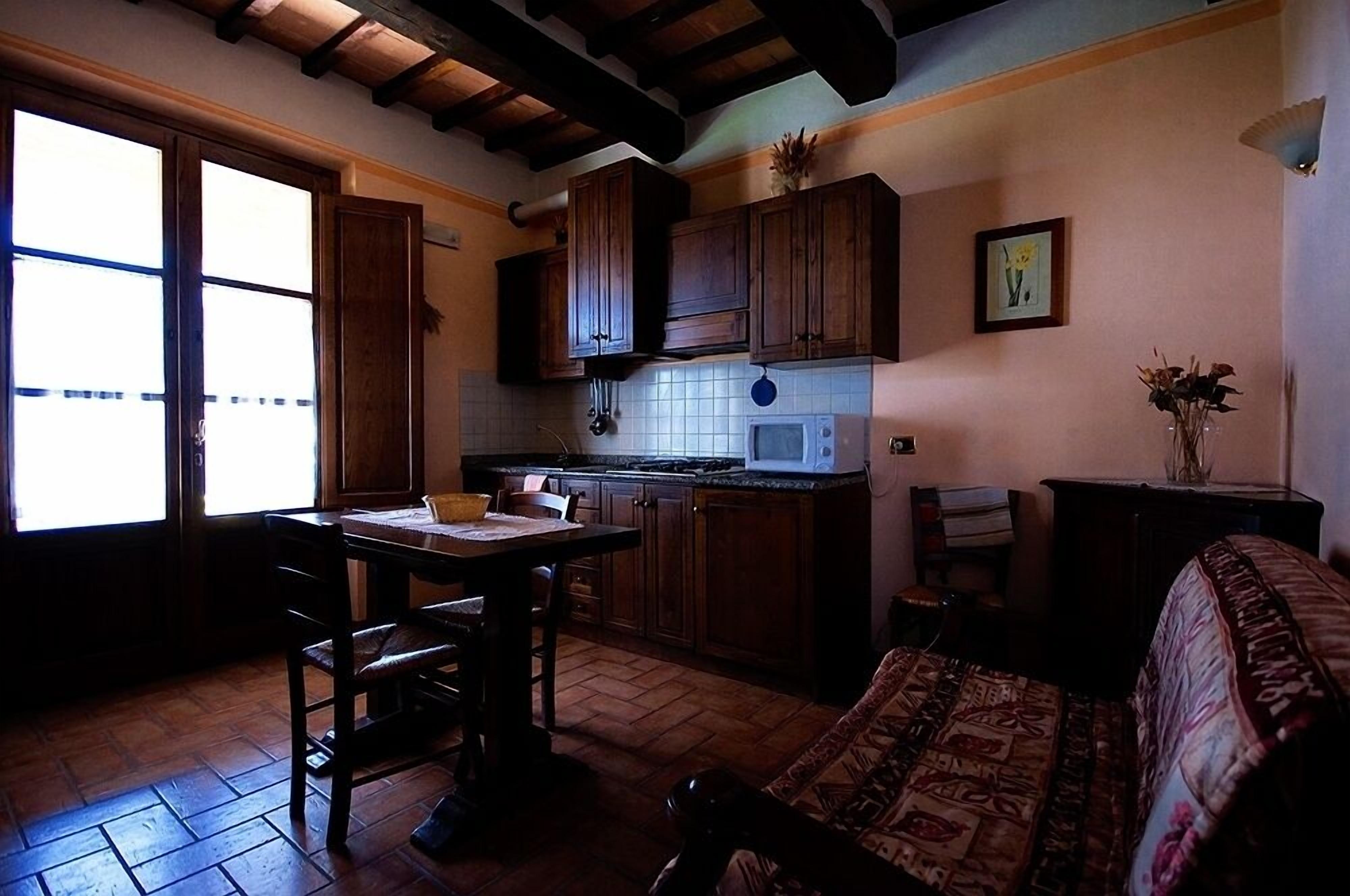 Una cocina con armarios de madera, salpicadero de azulejos y un comedor con mesa y sillas.