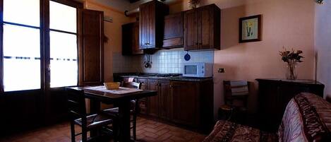 Una cocina con armarios de madera, salpicadero de azulejos y un comedor con mesa y sillas.