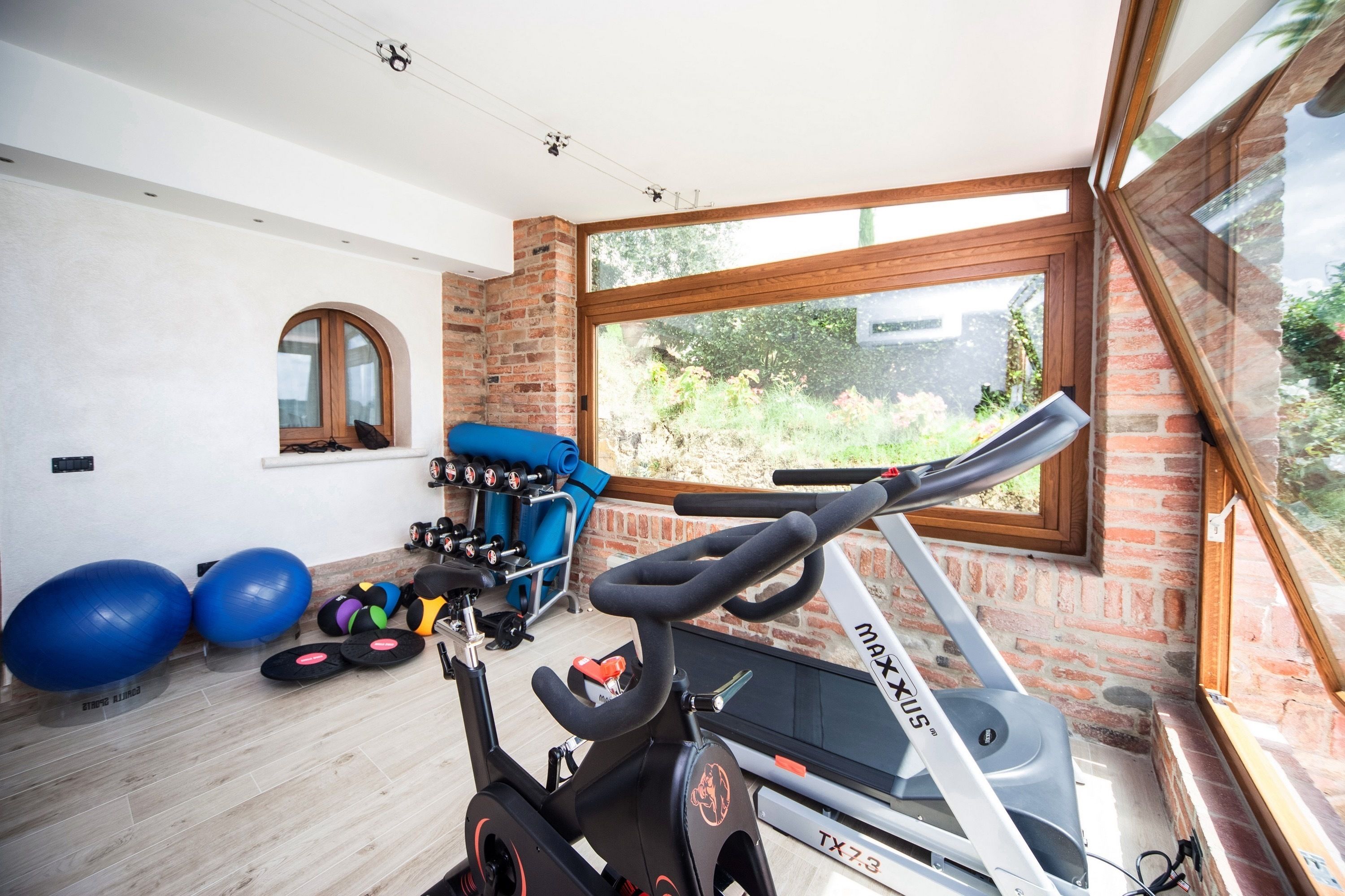 A home gym with exercise equipment, including a treadmill, stationary bikes, and exercise balls.