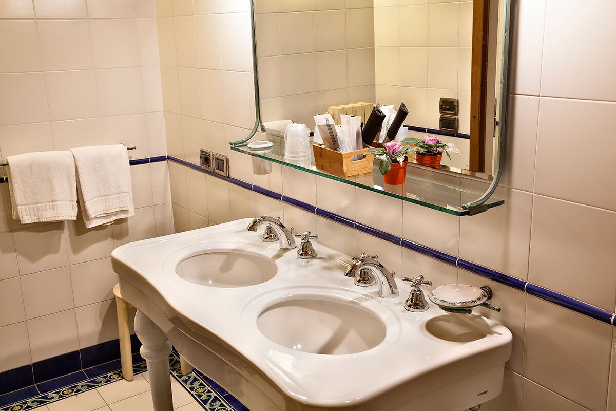 A bathroom with two sinks, a mirror, and a shelf with toiletries.