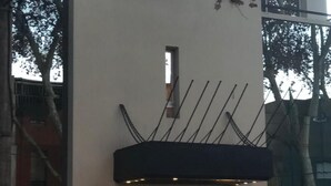 Un edificio moderno con fachada plana, una entrada central con un alero oscuro y una pequeña ventana sobre la puerta.