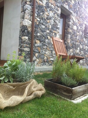 A stone building with a wooden chair and potted plants in the foreground. - Il Casale del Giglio (Santo Stefano di Magra)