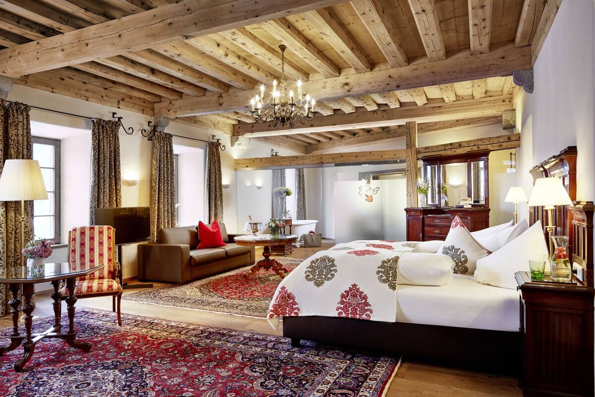 A spacious room with a large bed, a sofa, and a television.