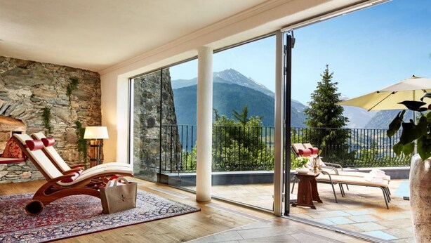 A spacious room with a large sliding glass door leading to a balcony with a mountain view.