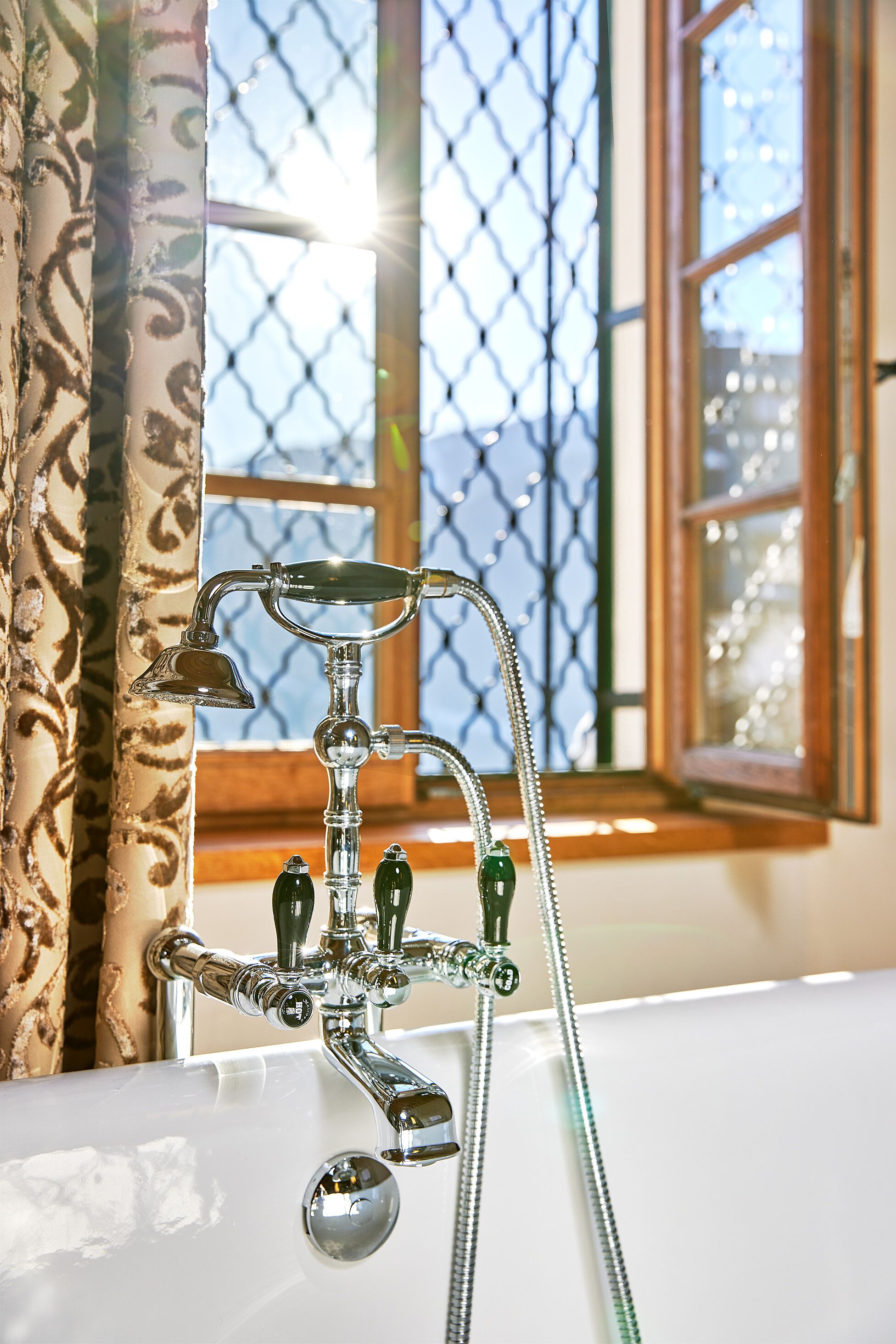 A bathroom with a classic bathtub, a shower, and a window with a view of a building.