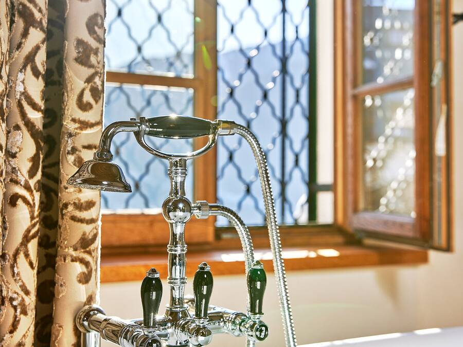 A bathroom with a classic bathtub, a shower, and a window with a view of a building.