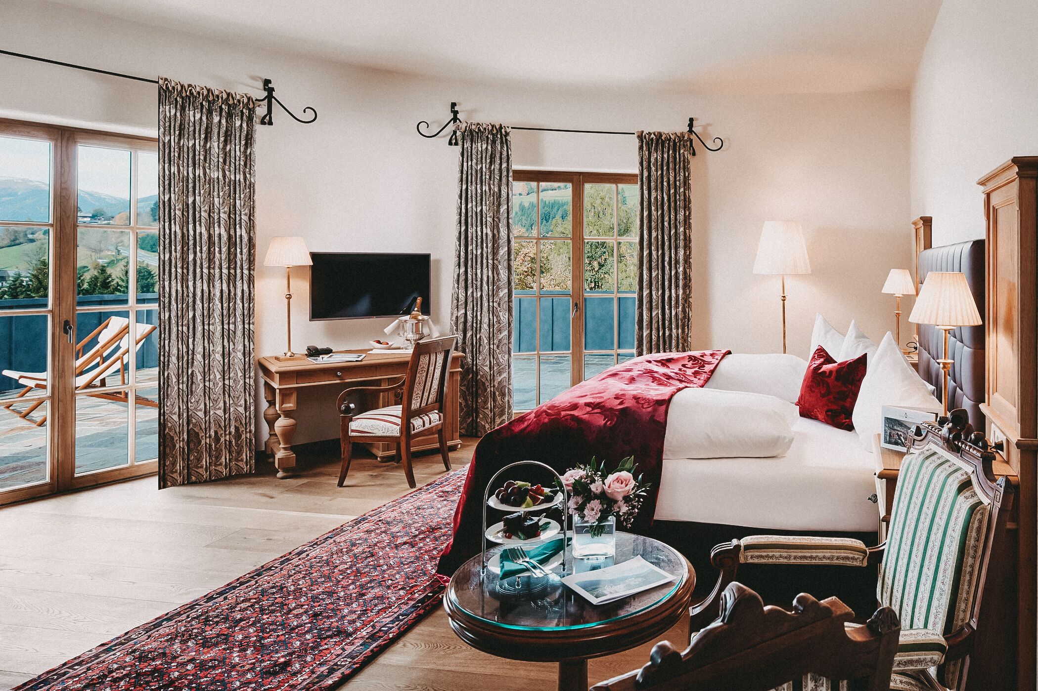 A bedroom with a bed, a desk, a TV, and a balcony.