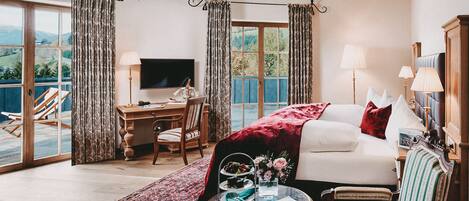 A bedroom with a bed, a desk, a TV, and a balcony.