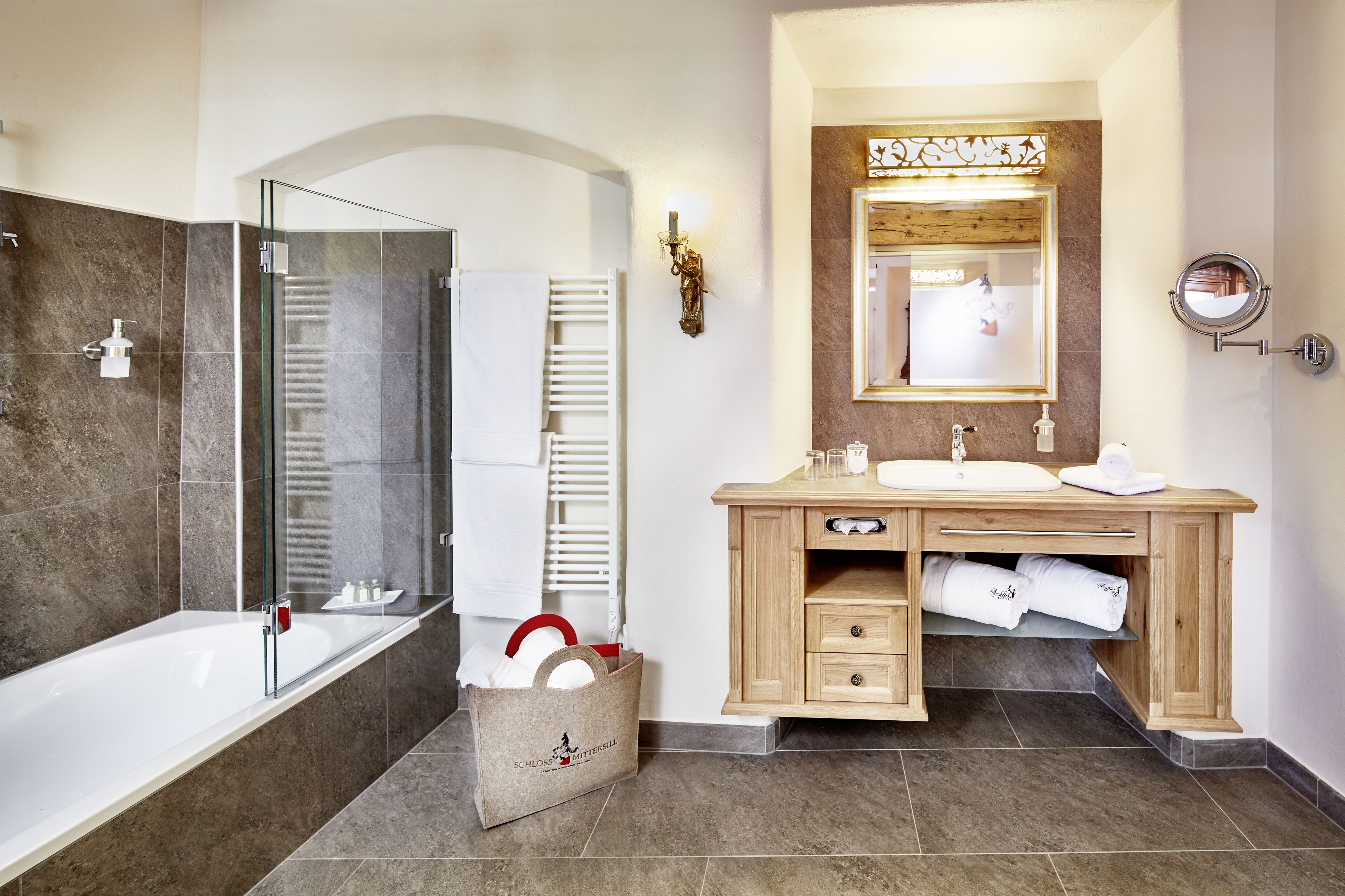 A modern bathroom with a glass-enclosed shower, a wooden vanity with a mirror, and a bathtub.