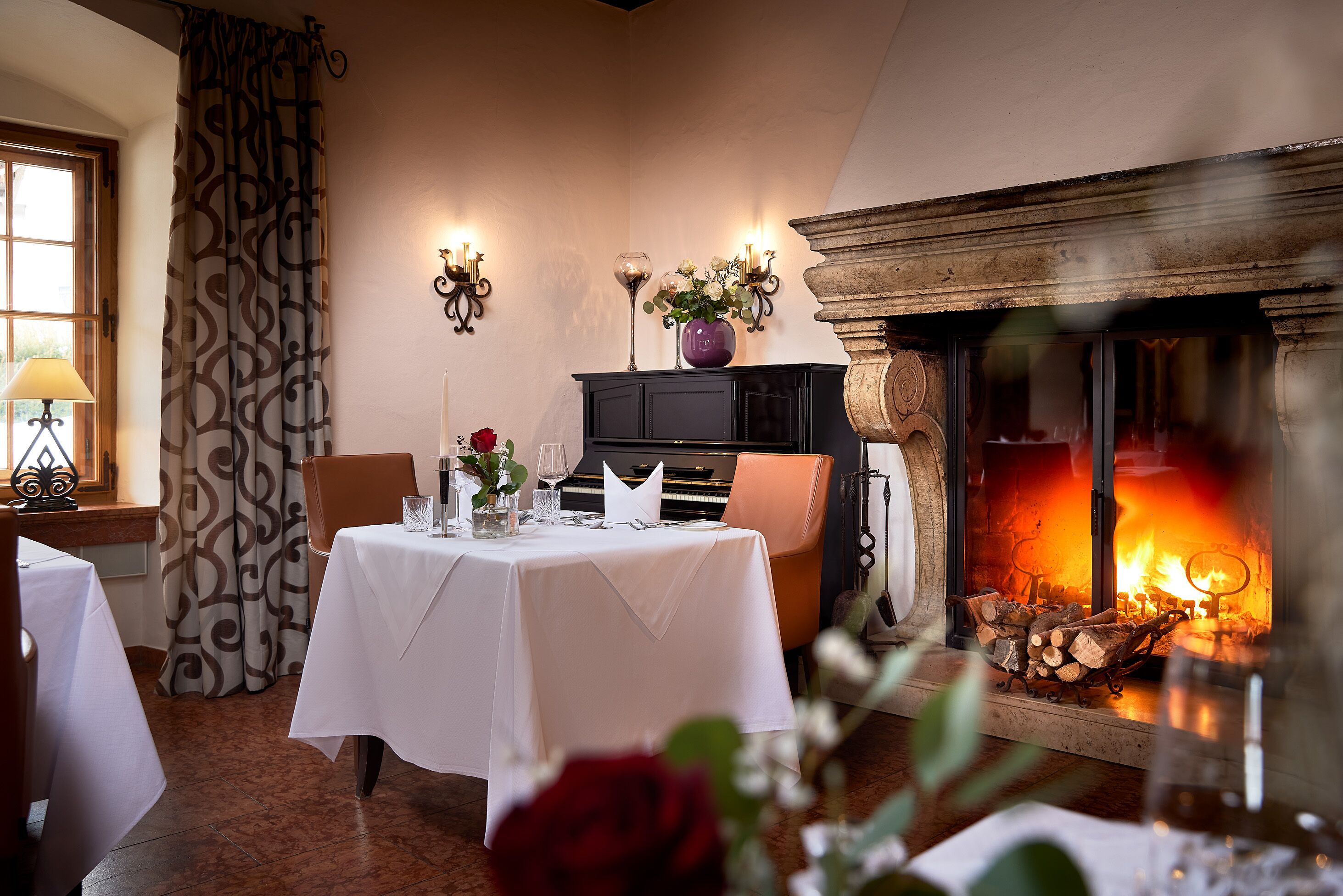 Ein Essbereich mit Kamin, einem Tisch für zwei Personen und einem Klavier im Hintergrund.