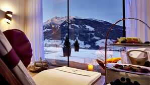 A room with a large window offering a view of snow-covered mountains.