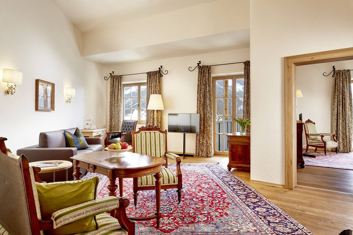 A spacious living room with a large wooden table, a sofa, and a TV.