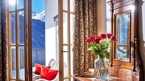 A room with a large window, a vase with red roses, and a wooden cabinet.