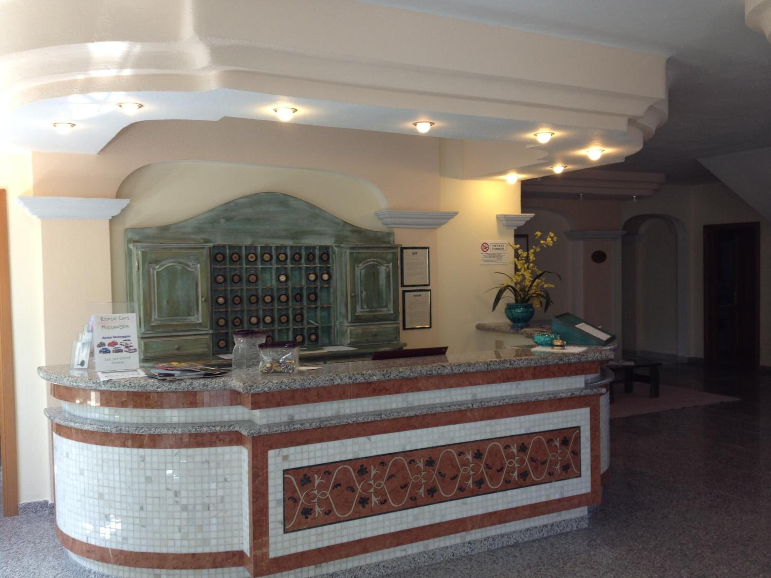 A reception area with a tiled counter, a green decorative panel, and framed certificates on the wall.