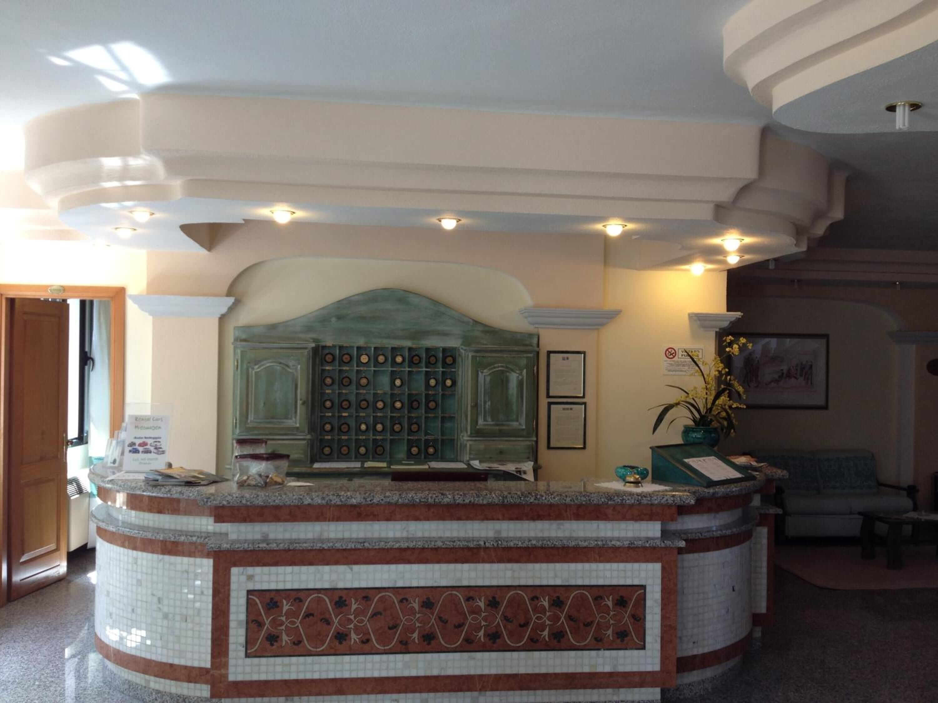 A reception area with a marble counter, a green decorative panel, and a framed certificate on the wall.