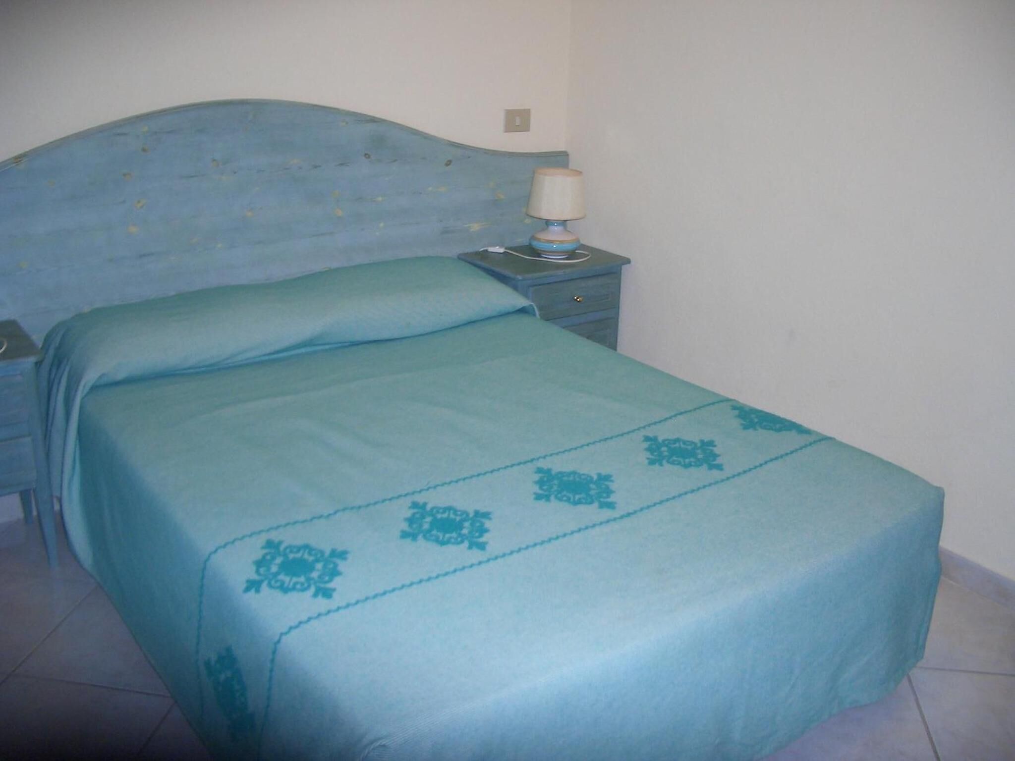 A bedroom with a bed, a nightstand, and a lamp.