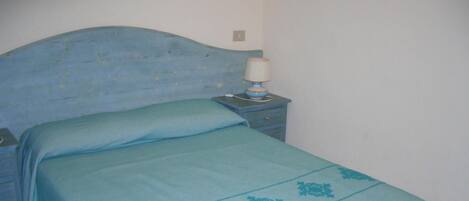 A bedroom with a bed, a nightstand, and a lamp.