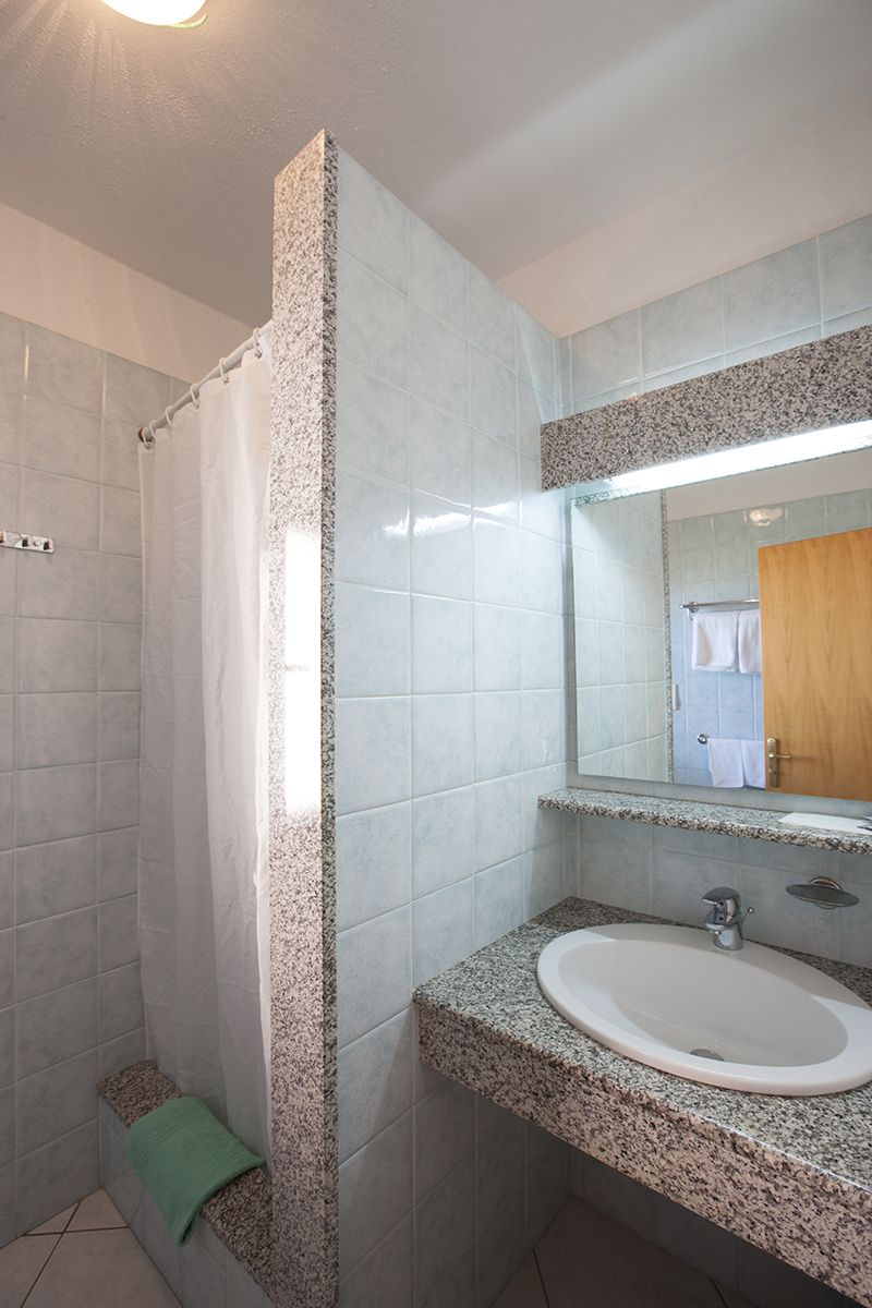 A bathroom with a shower, a sink, and a mirror.