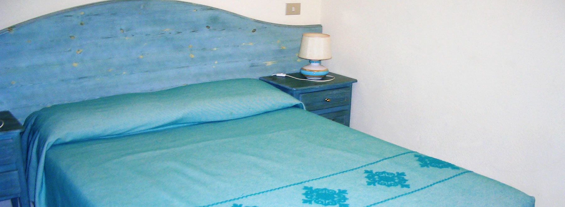 Una cama con cabecera y colcha azules.