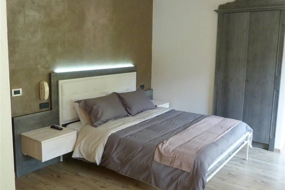A bedroom with a bed, bedside table, and a wardrobe.