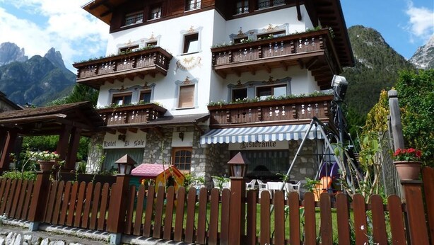 A multi-story hotel with balconies, a restaurant, and a wooden fence. - Hotel Al Sole (Auronzo di Cadore)