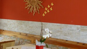 A room with a wooden headboard, a wall-mounted sun decoration, and a vase with white flowers. - Hotel Al Sole (Auronzo di Cadore)