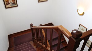 Un escalier en bois avec une rampe, un luminaire fixé au mur et deux tableaux encadrés accrochés au mur.