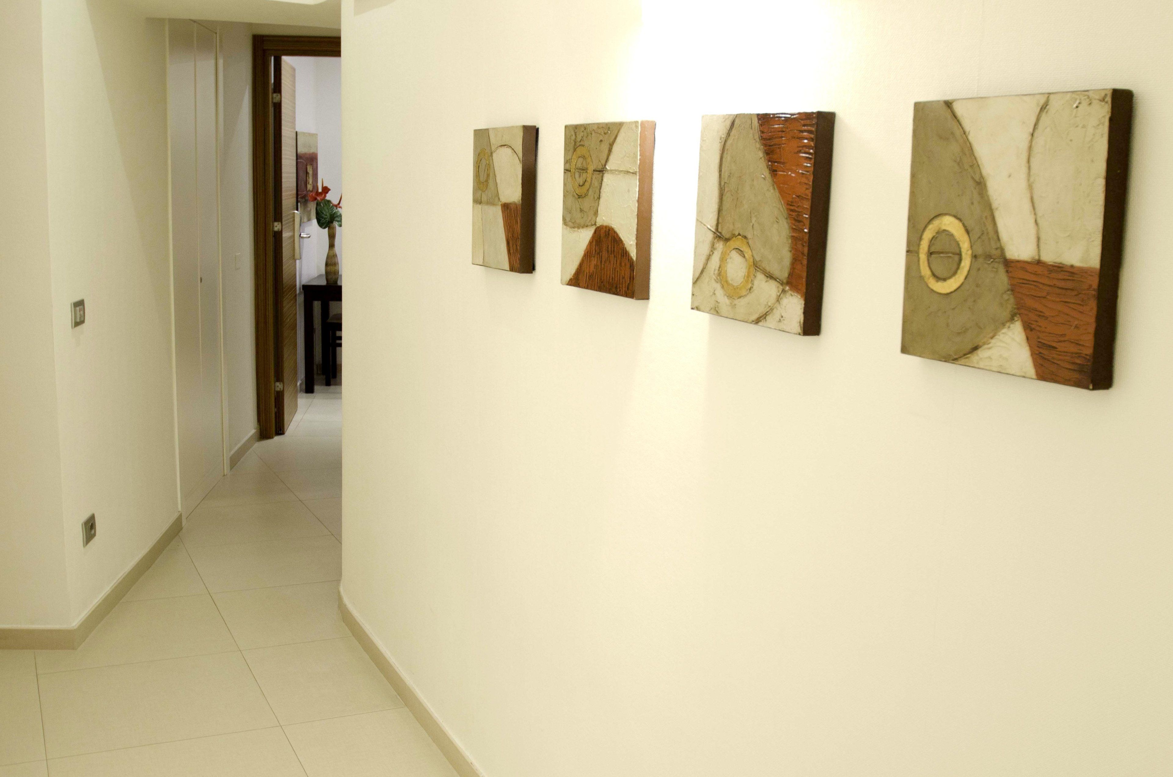Un couloir orné de quatre tableaux abstraits.