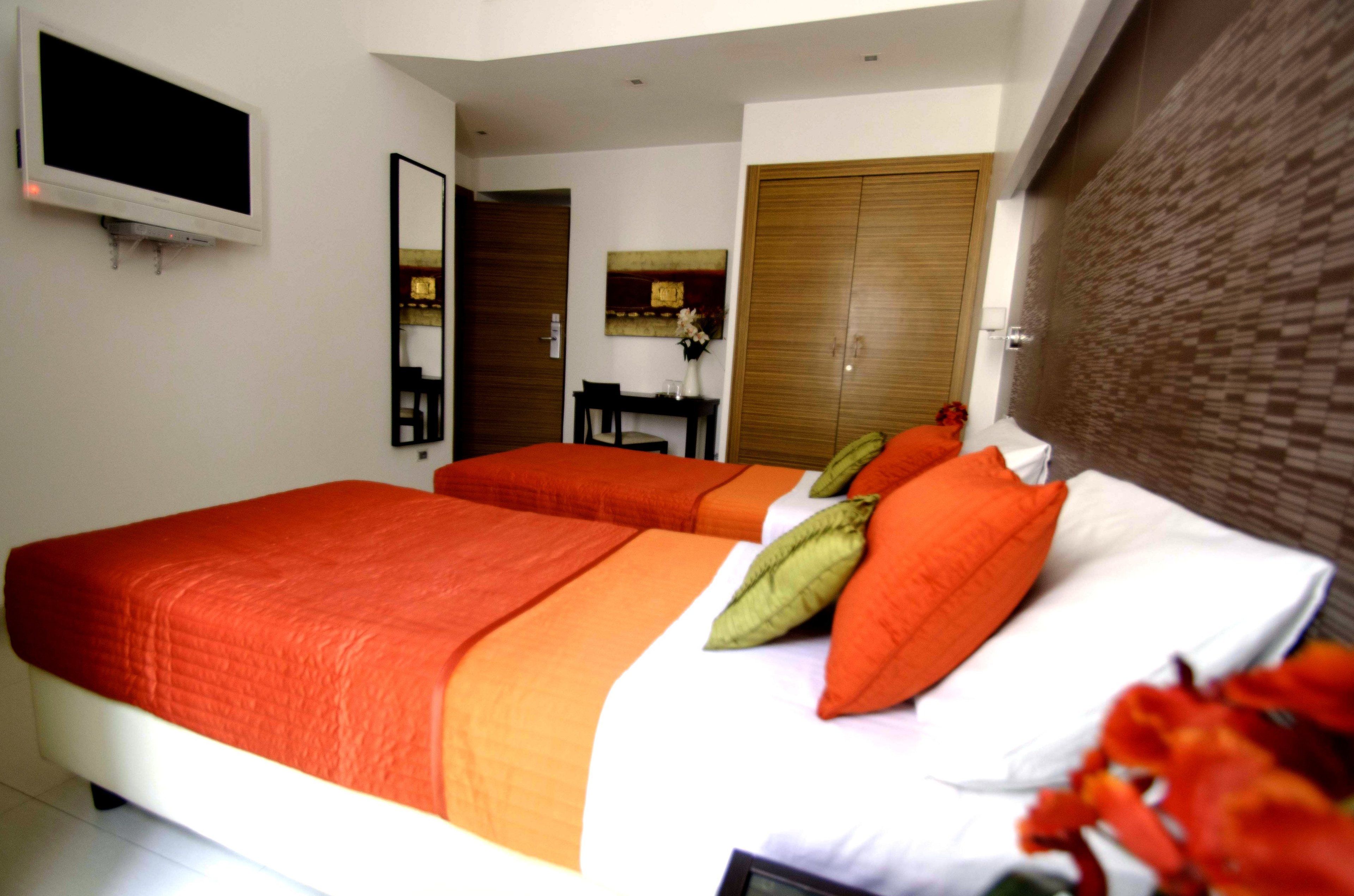 A hotel room with two beds, a TV, a desk, and a mirror.
