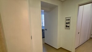 A hallway with white walls, a tiled floor, and a door on the left. - Interno 5 (Rome)